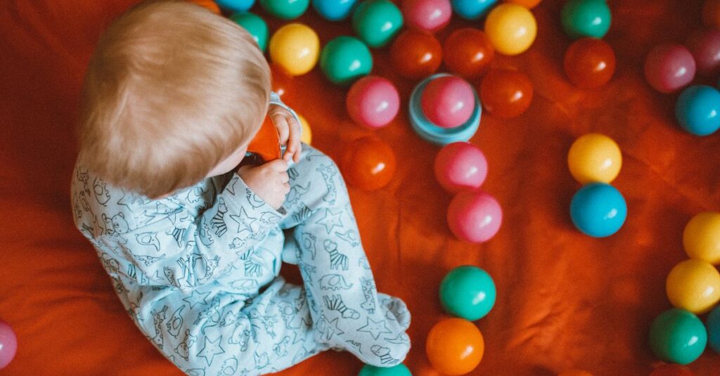 安全グッズに囲まれた室内で1歳の双子が遊ぶ様子。保護者が少し離れて見守りながらも安心できる空間。