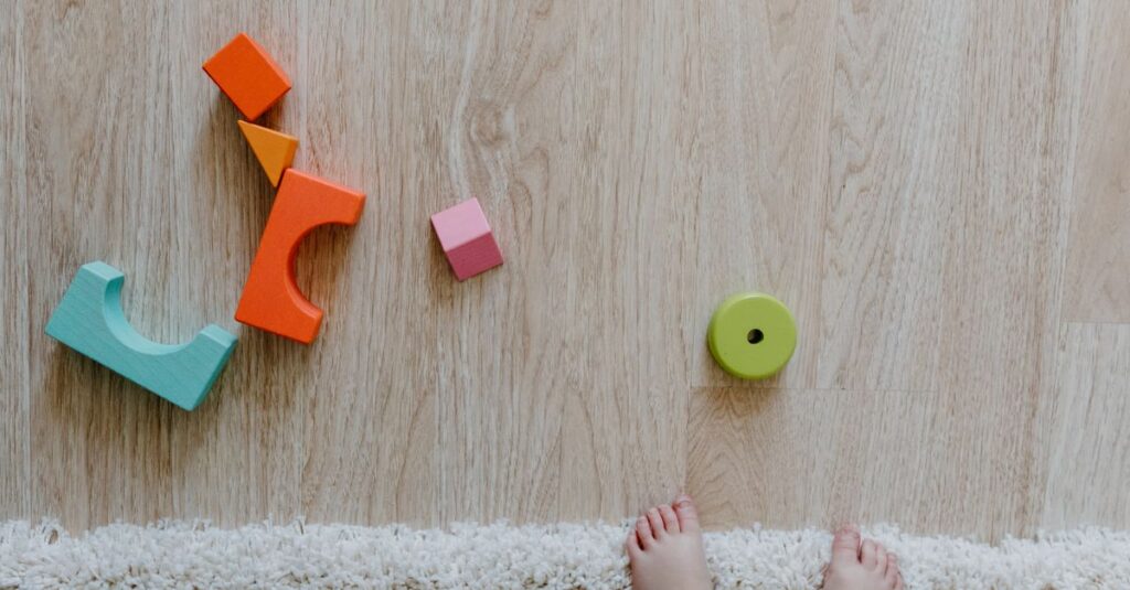 1歳の双子が安全な室内スペースで遊んでいる様子。マットが敷かれ、家具の角もガードされている安心な環境。
